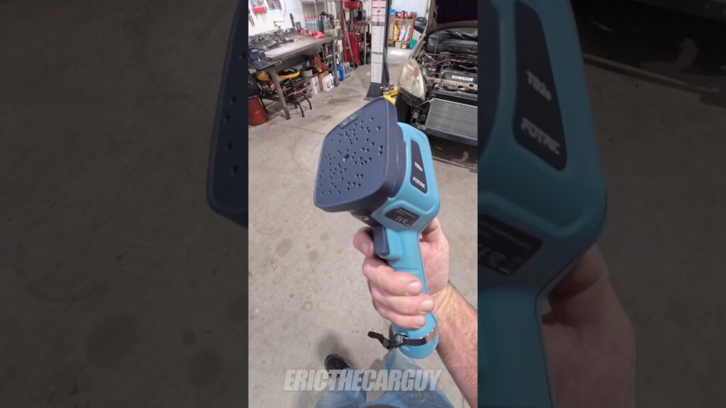 A person holding a FOTRIC TD2e Acoustic Camera near a vehicle door seal to detect wind noise.