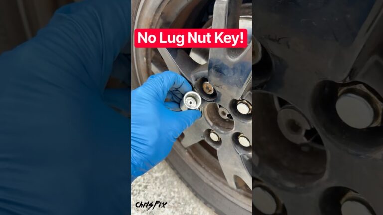 A person using a hammer to seat an impact-rated socket onto a locking lug nut on a car wheel.